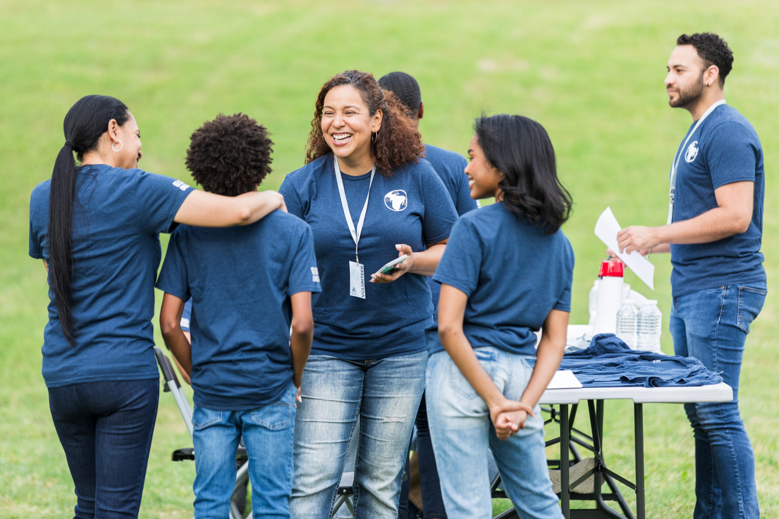 Diverse group of smiling volunteers working together outdoors. Community event.