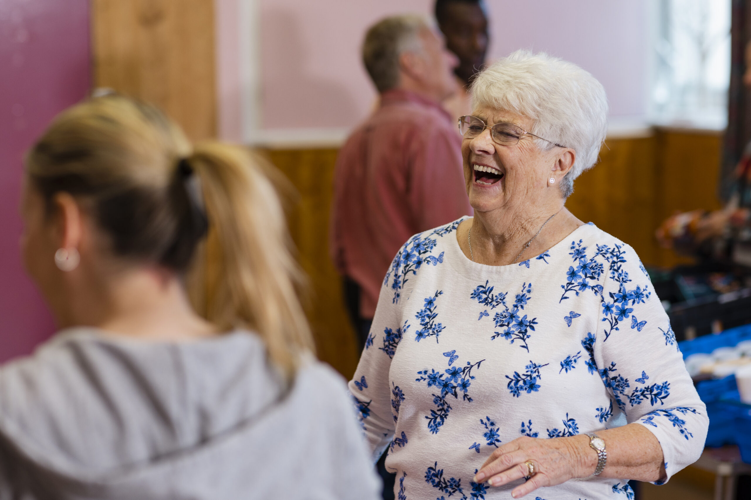 Community church in the North East of England running a soup kitchen and warm hub. People in need are meeting there. Focus on one woman laughing to a person off camera.